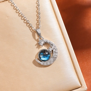 Close-up of crescent moon necklace with blue sandstone and inlaid sparkling crystals