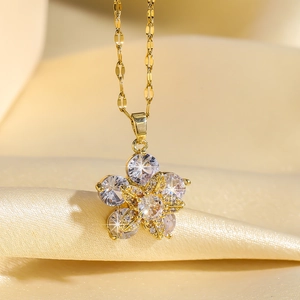 Gros plan d'un collier pendentif fleur dorée rotative avec zircons roses et blancs