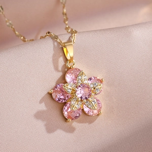 Détail macro d'un pendentif fleur rose rotatif avec zircone sur fond de soie douce