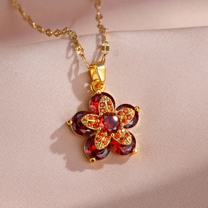 Détail macro du pendentif fleur rotative avec pierres rouges et chaîne dorée sur satin