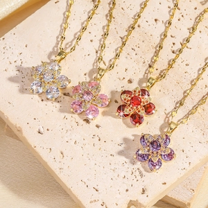 Détail de quatre pendentifs fleurs en zircon coloré rose rouge et blanc sur chaînes
