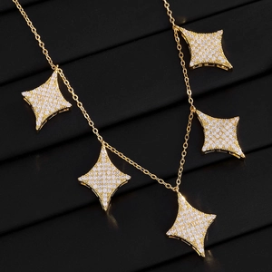 Macro detail of gold necklace with sparkling full-diamond four-point star pendants
