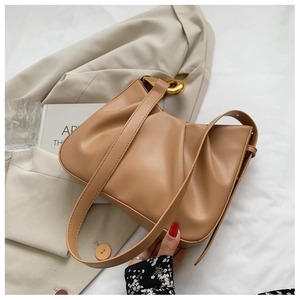Detail of khaki pleated cloud bucket bag with gold ring buckle on beige blazer