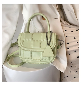 Detail view of mint green crossbody bag with 3D bear relief and metal chain charm