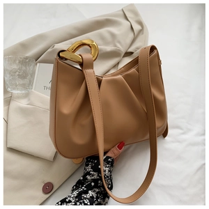 Detail of caramel pleated bucket bag with bold gold chain and soft PU leather texture