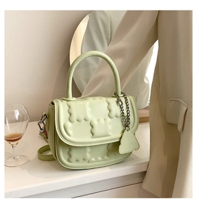 Detail view of light green quilted handbag with silver chain and 3D geometric patterns
