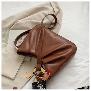 Detailed shot of brown pleated cloud bag with prominent gold metal ring and strap