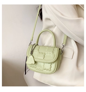 Detail of mint green crossbody bag with wavy quilted texture and metal chain