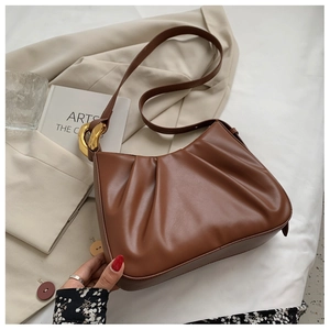 Close-up of brown pleated cloud bucket bag with decorative gold geometric metal buckle