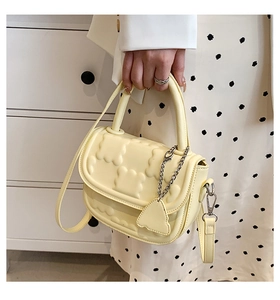 Detail of pale yellow crossbody bag featuring 3D bear texture and metal charm