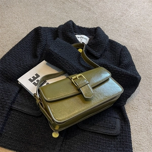 Vintage olive green faux leather underarm bag with retro metal buckle on tweed background