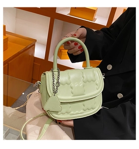 Detail of light green quilted handbag with bear charm and silver chain strap
