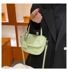 Detail of mint green saddle bag with bear embossing and silver chain decoration