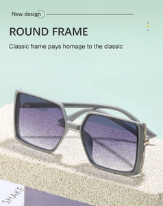 Detail view of purple gradient lenses and gold hinge decor on grey oversized sunglasses