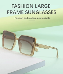 Detail of light amber square sunglasses with golden hinges on a soft green background