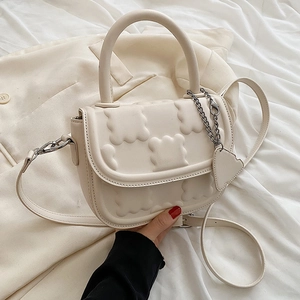 Chic cream leather crossbody bag with quilted cookie texture and heart charm
