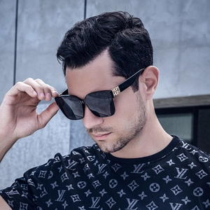 Detail of black square sunglasses with gold metal geometric temple accents on a model