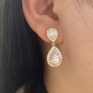 Close-up of sparkling waterdrop cubic zirconia earrings on model with golden finish