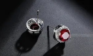 Macro view showing the prong setting and faceted red zircon detail on silver stud earrings