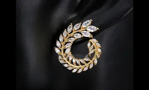 Close-up of golden leaf-shaped ear studs featuring white marquise-cut zircon stones