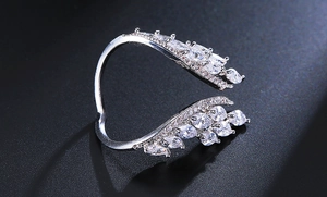 Macro detail of silver wings ring with cubic zirconia feathers on black background