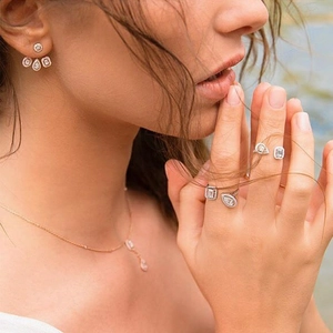 Close-up of rose gold jewelry set with geometric zircon studs and open ring on model