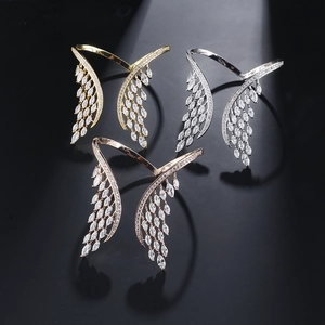 Vue détaillée de joncs ouverts en forme d'ailes en or, argent et or rose sertis de zircons