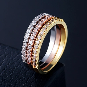 Macro view of three stacked adjustable rings in silver, gold, and rose gold with AAA zircon