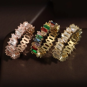 Three baguette-cut zircon eternity rings in gold and rose gold on dark leather