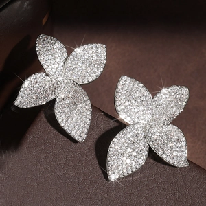 Elegant four-leaf flower stud earrings with micro-pave cubic zirconia on a luxury display