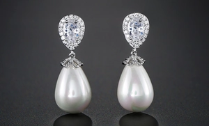 Macro detail of drop pearl earrings with silver metal and oval-cut zircon inlay