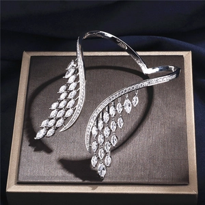 Bracelet manchette d'aile argenté avec pierres marquise posé sur une boîte dorée