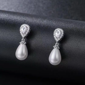 Elegant teardrop pearl earrings with zircon inlay on a premium black leather surface
