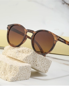 Detail of tortoiseshell frame sunglasses with brown gradient lenses on stone display