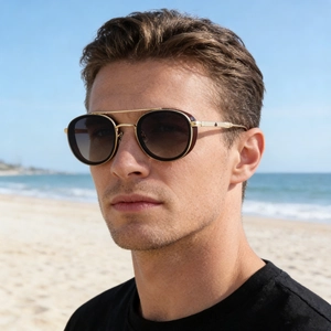 Retro oval metal sunglasses with gold frame and gradient lenses on a beach model