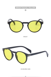 Close-up of retro black oval sunglasses with yellow lenses and silver arrow hinge detail