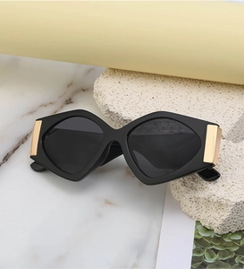 Detail showing oversized geometric sunglasses with golden metal hinges and black frame