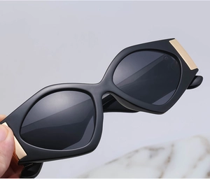 Detail view of thick black frame sunglasses with decorative gold metal accents on sides
