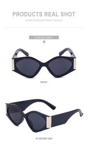 Close-up of black cat-eye sunglasses with gray lenses and gold square metal accents