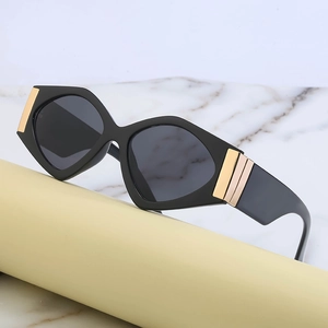 Modern geometric black frame sunglasses with luxury gold accents on marble base