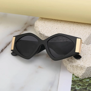 Fashionable black geometric sunglasses with gold metal accents against a stone backdrop