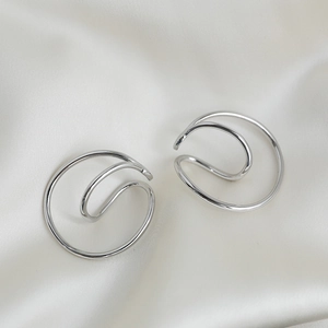 Detailed macro view of silver Mobius double-layered ear cuffs on soft silk background