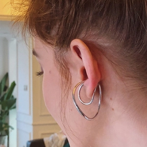 Close-up of a silver double-layered ear cuff worn on earlobe without piercings