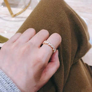 Dettaglio dell'anello ondulato in oro con zirconi indossato sul dito della mano