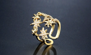 Makroaufnahme goldener Sternenring mit Zirkon-Inlay auf dunklem, texturiertem Hintergrund