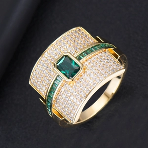 Macro detail of gold ring featuring large green emerald-cut stone and pavé zircon accents