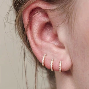 Three-piece gold micro-pave cubic zirconia hoop earrings stacked on earlobe