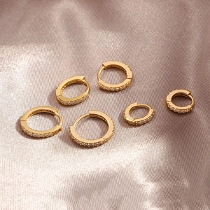 Set of six gold hoop earrings with pavé cubic zirconia on champagne silk background