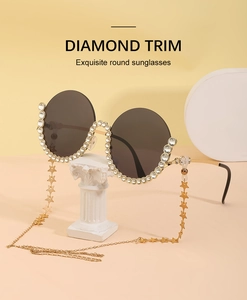 Detail einer runden Sonnenbrille mit Diamantbesatz und goldener Sternenkette Deko