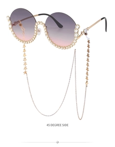 Detailansicht der runden lila Sonnenbrille mit Kristallen und goldener Sternenkette im 45-Grad-Winkel